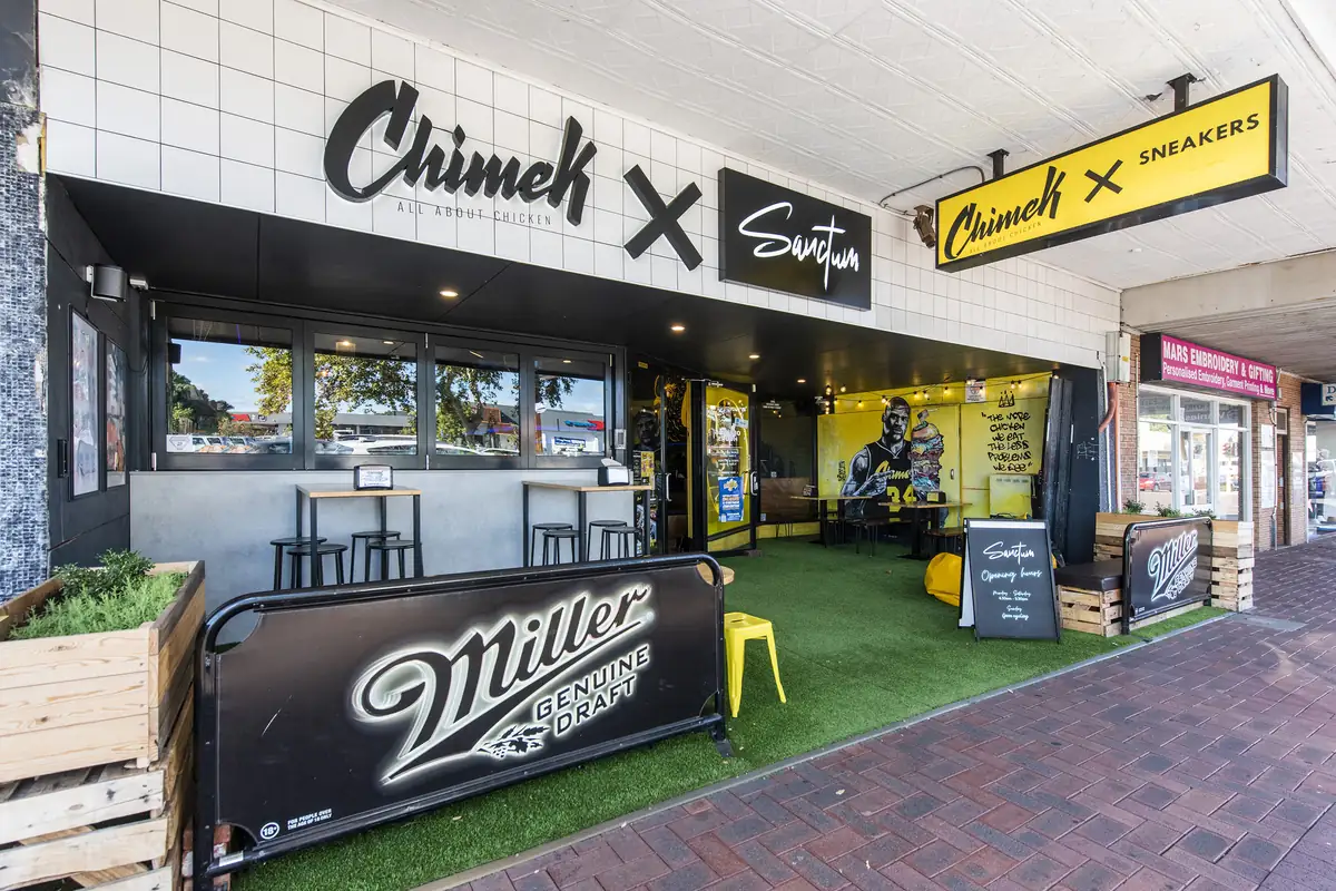 Completed food and beverage tenancy — shopfront with signage, roller shutter and planter seating to the footpath.