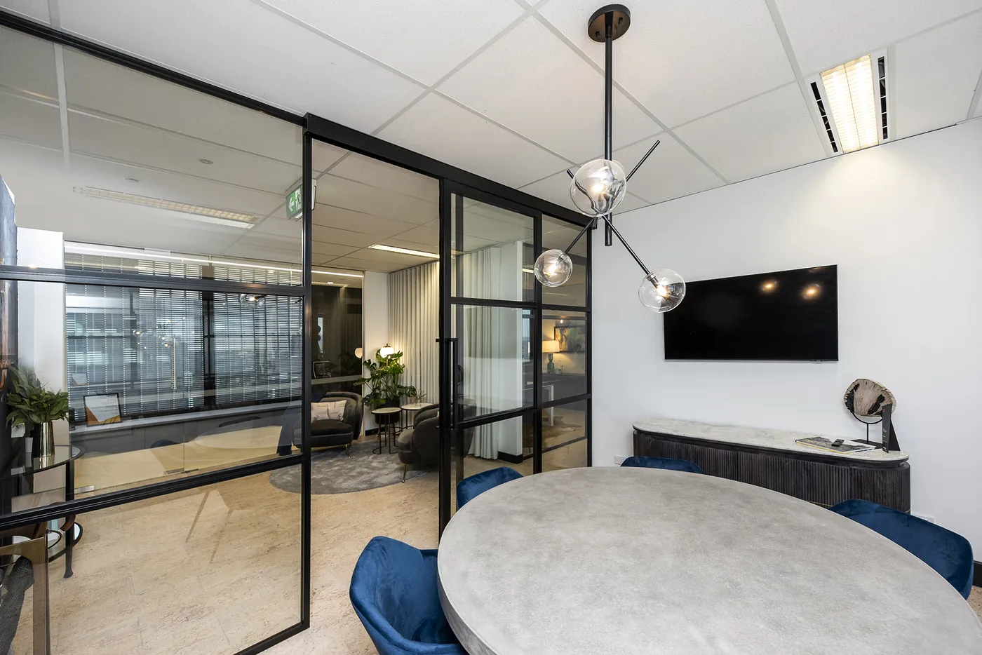 Benchmark — Boardroom with pendant lighting, concrete table and blue velvet seating.